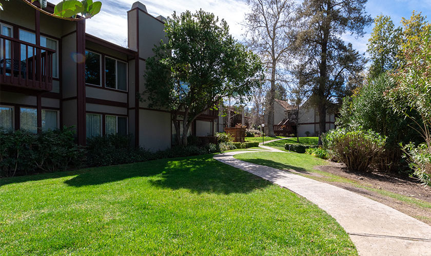 walkway at San Diego Country Estates along green grass with beige buildings with dark brown trim