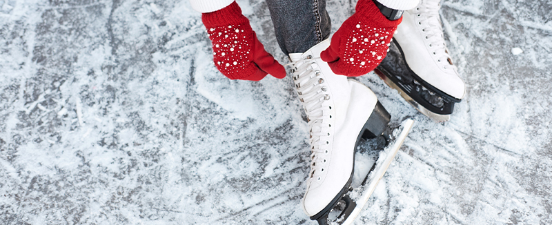 Lacing up ice skates with red mittens on