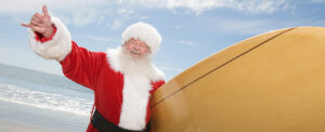 Man dressed as Santa holding a surfboard